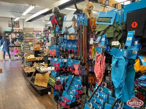 Bruce's Pet and Farm Supply store interior displaying a wide selection of pet products, including harnesses, leashes, and dog apparel from popular brands. The shelves feature a variety of dog toys, treats, and training tools, with customers browsing the aisles. The store offers essential supplies for pet owners in Maple Ridge, providing high-quality items for pets of all sizes.