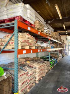 Bruce's Pet and Farm Supply warehouse shelves fully stocked with a variety of animal feed bags, including Otter Co-op and Lifeline brands. Pallets are neatly arranged with large feed bags for livestock, ensuring ample supply for customers. The organized storage space supports the needs of local farmers and livestock owners in Maple Ridge, providing high-quality feed options for a range of farm animals.